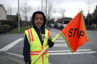 Avery Barley is one of the Elizabeth Blackwell Elementary students who volunteer their time to help ease the traffic situation in front of the school. His smile doesn’t quite hide the problem of the serious traffic congestion you can see behind him.