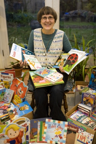 Ann Fletcher sits among a large pile of both English and Spanish language children’s books she obtained for the Book Shelf Program that gives books to kids in the Issaquah area.