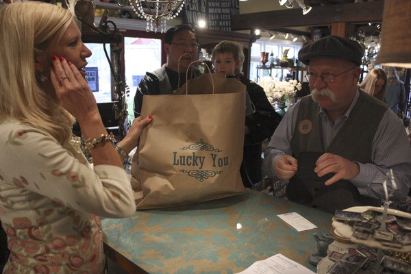 Lucky You! owner Denise Jensen hands Bill Glassey his purchase during Issaquah's first-ever Cash Mob in April.