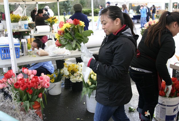 Maria Cha ties up flowers from Carnation at the Issaquah Farmers Market opening day. While produce was still lean