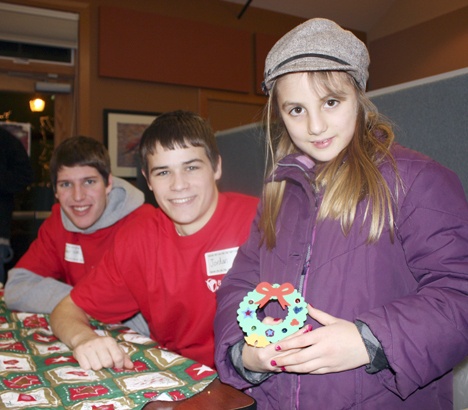 Ella Hikes shows off her Christmas tree ornament fashioned by Issaquah High School wrestling team captains Tyler Volk and Jordan Tanner. The high-school wrestlers volunteered their time and handiwork to earn their varsity letters for wrestling.