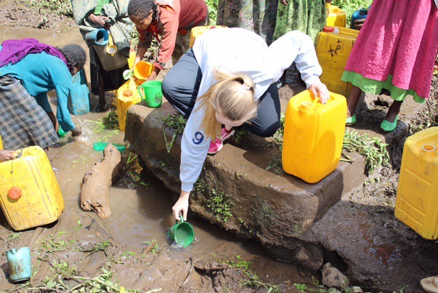Eastside Catholic teen Giuliana Sercu scoops muddy drinking water into jugs during her trip to Ethiopia.