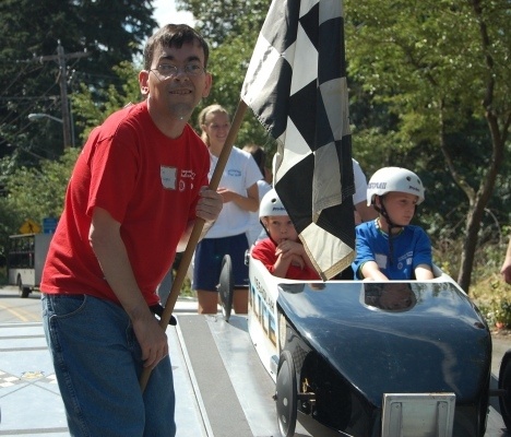 Race starter Tim Finnegan checks that the course is clear before giving the drivers the checkered flag at the Issaquah Rotary Challenge Day Soapbox Derby on Saturday.