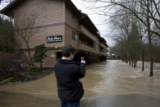 Ryan Laursen takes a picture with his cellular phone at the Park Shore Apartments in Issaquah. The Issaquah Creek flooded the lower units on the building.
