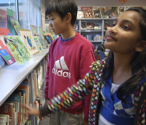 Apollo Elementary School 5th grade students Keane Wong and Aashika Jhawar have a look at the Reflection art program entries of their fellow students in the school's library on Monday.
