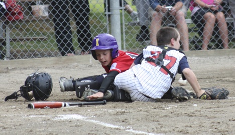 Issaquah 10-11 year-old All-Star Gunnar Erickson reaches for home after a collision with the Bellevue West catcher Tuesday. Erickson was safe on the play as Issaquah went on to win