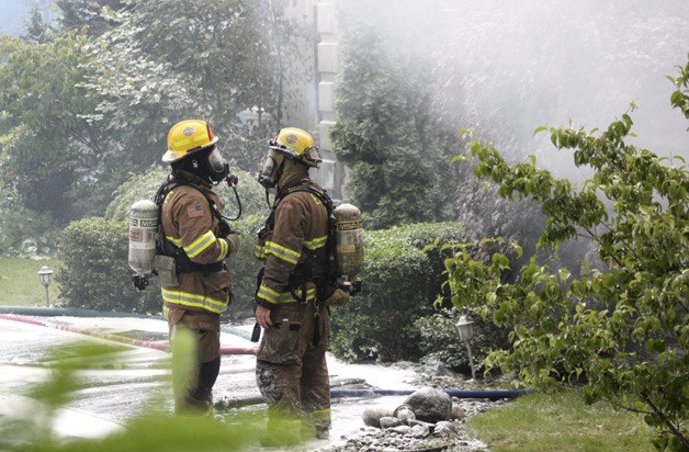 Firefighters stand at the ruins of a house fire that began just before noon June 29