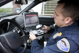 Officer Brian Horn demonstrates the new SECTOR system installed in his patrol car.