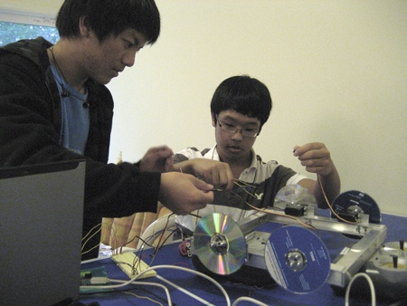David Woo and Wesley Lau work on creating a robot during one of StudentRND’s workshops this summer. The duo used CDs as wheels for the car.