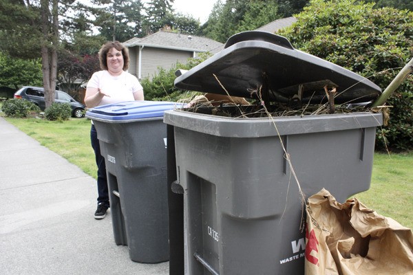Robin Rodney stands near her recycling and yard waste bins