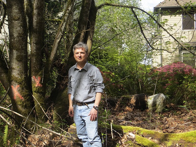 George Wangersky stands by a cluster of trees marked to be removed. His home is in the background.