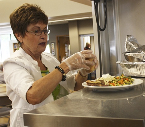 Janice Batchelder prepares plates for seniors during the Tuesday lunch at the Issaquah Senior Center. Batchelder started volunteering twice a week about a month ago as a way to give back. Local organizations