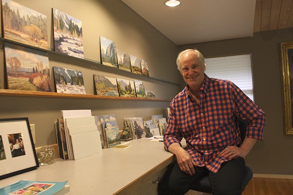 Sammamish artist Jim Lamb sits in his Pine Lake studio with several of his popular landscape pieces behind him.
