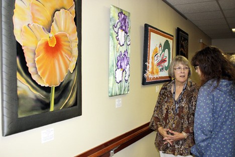 Arlene Carter promotes the Vibrant Threads art exhibit with a visitor prior to the Aug. 18 artist's reception at Providence Marianwood in Issaquah.