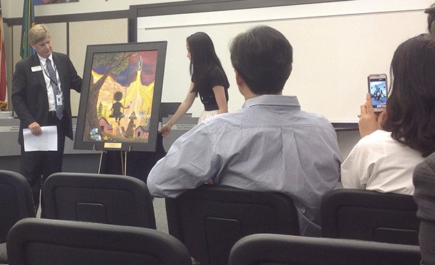 Superintendent Ron Thiele and Skyline freshman Julia Hong unveil her painting 'The Soaring Dream' in the School Board chambers. Hong's parents watch from the front row.
