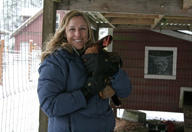 Sasha Visconty holds a hen inside a pen attached to her coop at her Tiger Mountain home.