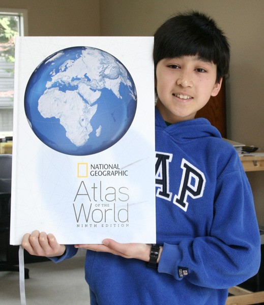 Arjun Kumar holds up his largest world atlas at his Issaquah home. The 13-year-old won the Washington state geography bee and is moving onto a national competition in Washington D.C. CELESTE GRACEY/Issaquah Reporter