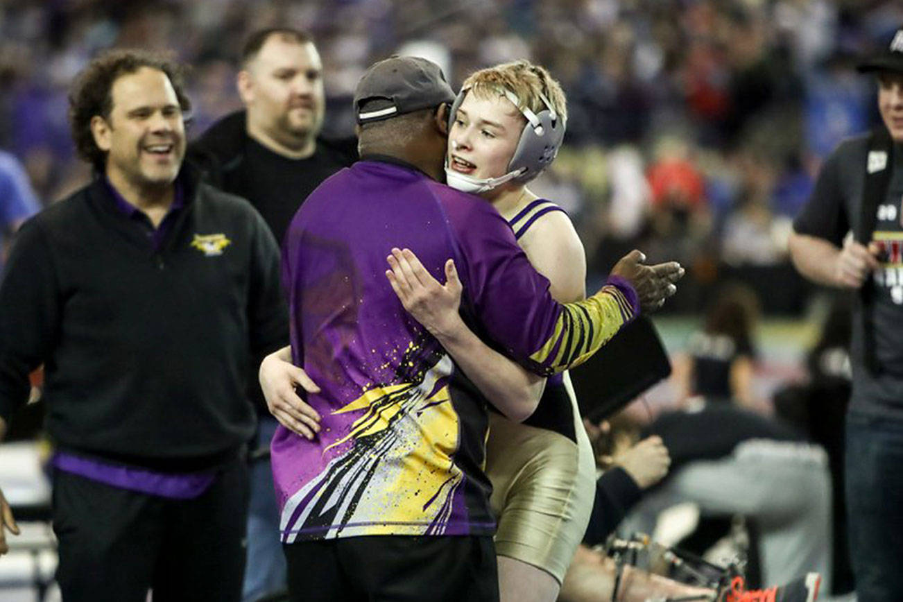 Photo courtesy of Don Borin/Stop Action Photography                                Issaquah Eagles 113-pound wrestler Carson Tanner, right, embraces Issaquah assistant coach Manny Brown after defeating Hanford’s Hunter Murphey in the Class 4A 113-pound quarterfinal matchup. Tanner earned sixth place in the Class 4A 113-pound weight division. Brown was named KingCo 4A assistant coach of the year during the 2017-18 season.