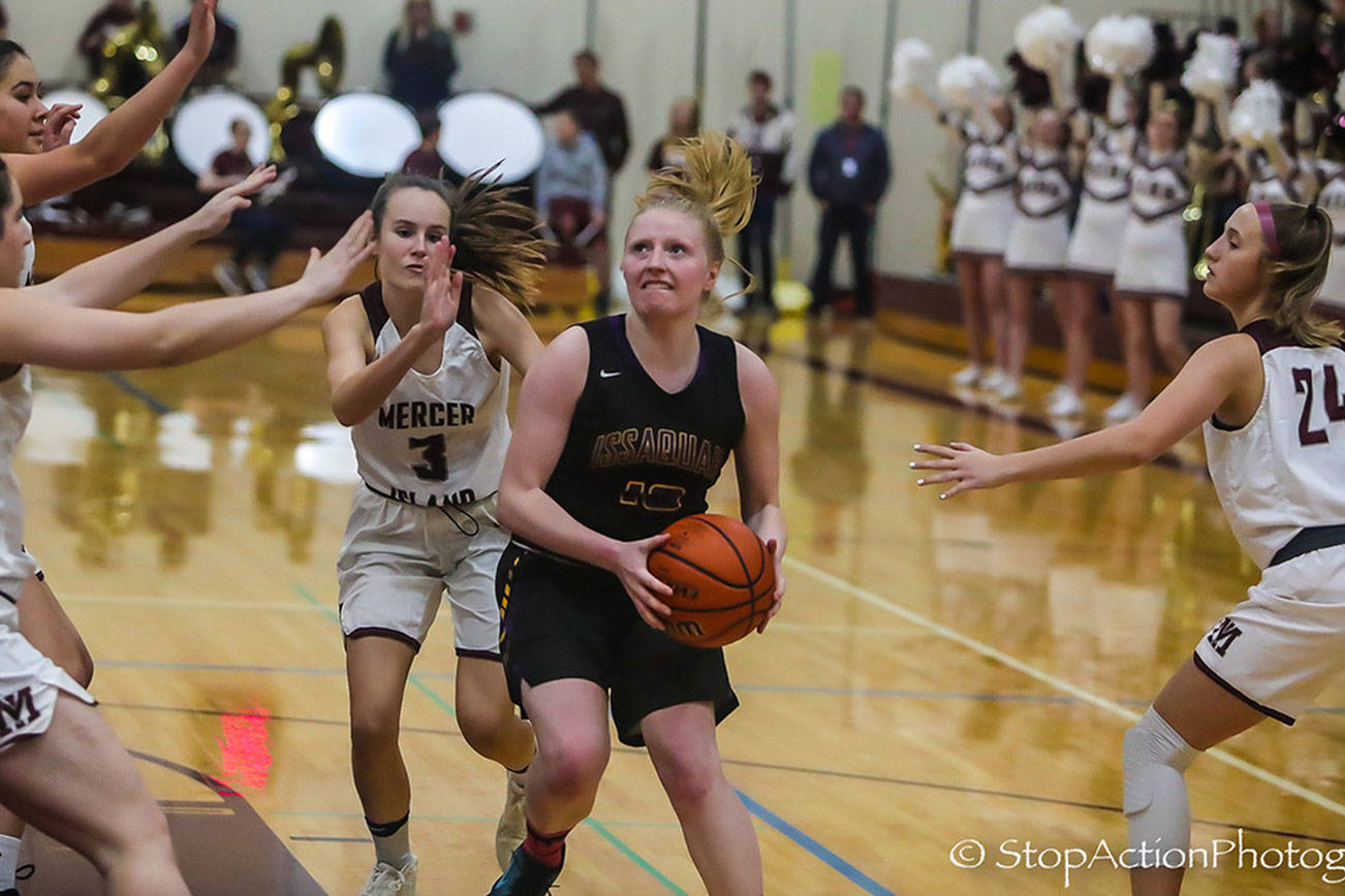 Issaquah Eagles senior Lucy Stewart (center) takes the ball to the hoop against the Mercer Island Islanders in a non-league game on Nov. 30. Photo courtesy of Don Borin/Stop Action Photography