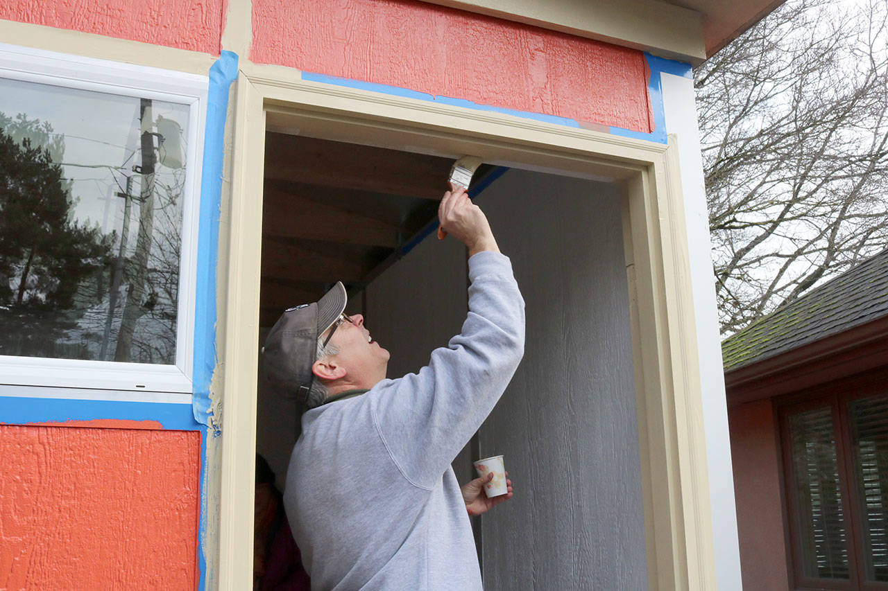 Jiff Searing paints the door frame of the tiny house during the volunteer event on Saturday. Evan Pappas/Staff Photo