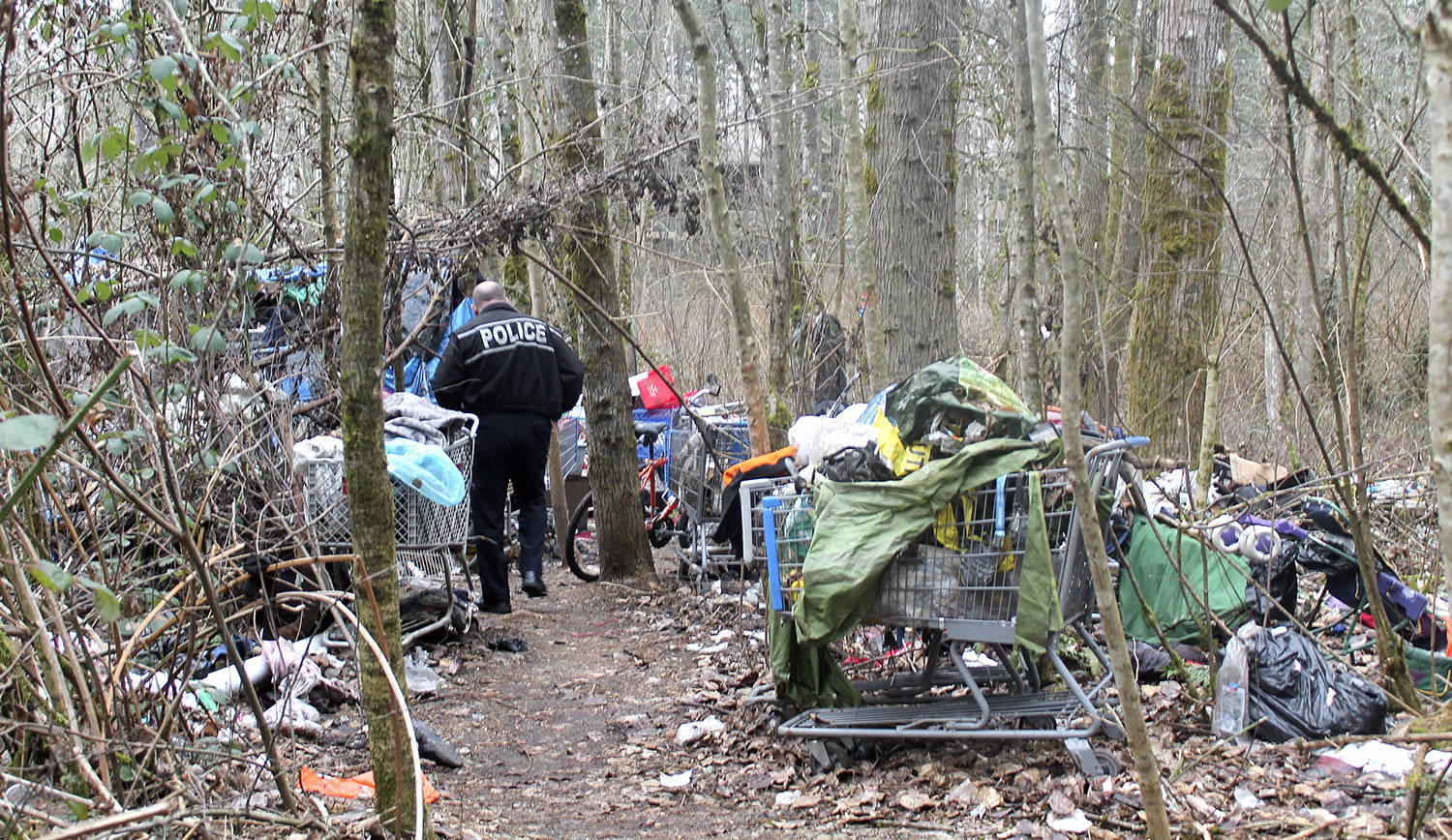 In this photo from January 2017, a Federal Way police officer walks through the remains of a homeless encampment in Federal Way. File photo