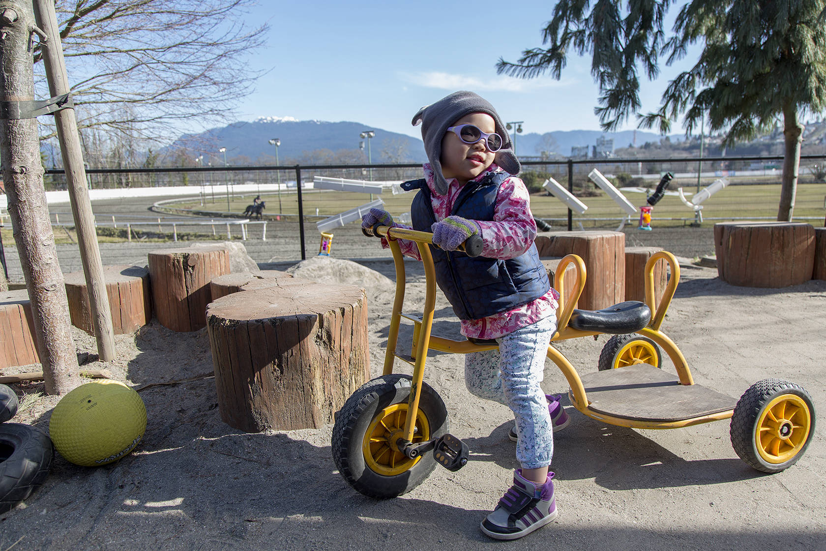 Vivian, one of many cared for at a child care center of the Kiwassa Neighbourhood House in Vancouver, B.C., spends the day outside on a tricycle on March 21. The site was awarded prototype status by the government of British Columbia as part of an effort to ease skyrocketing child care costs in the province. Ashley Hiruko/staff photo