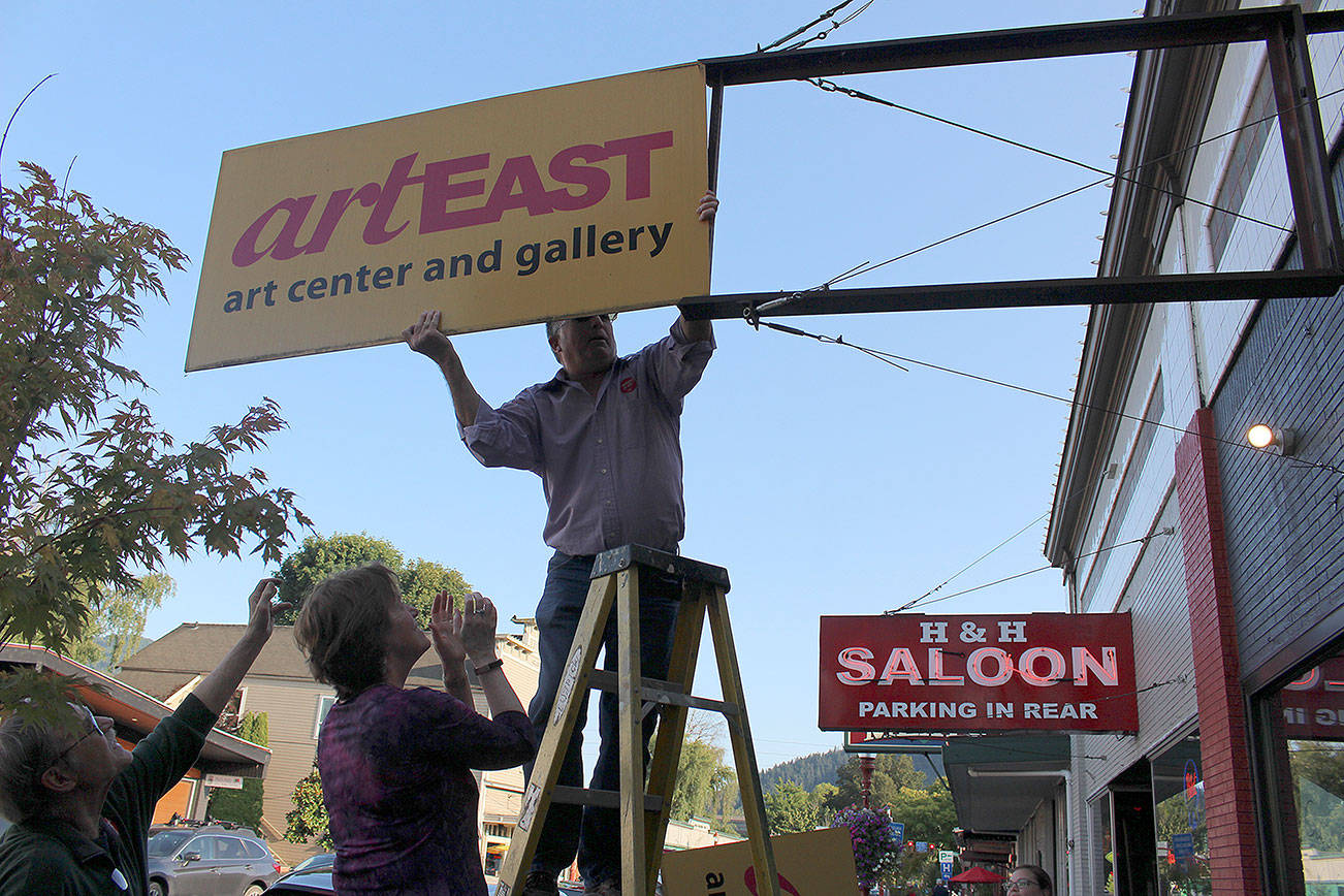 Mike Bossing removes the ArtEast sign during its closing party. From left: David Lutrick, Monica Phillips and Mike Bossing.