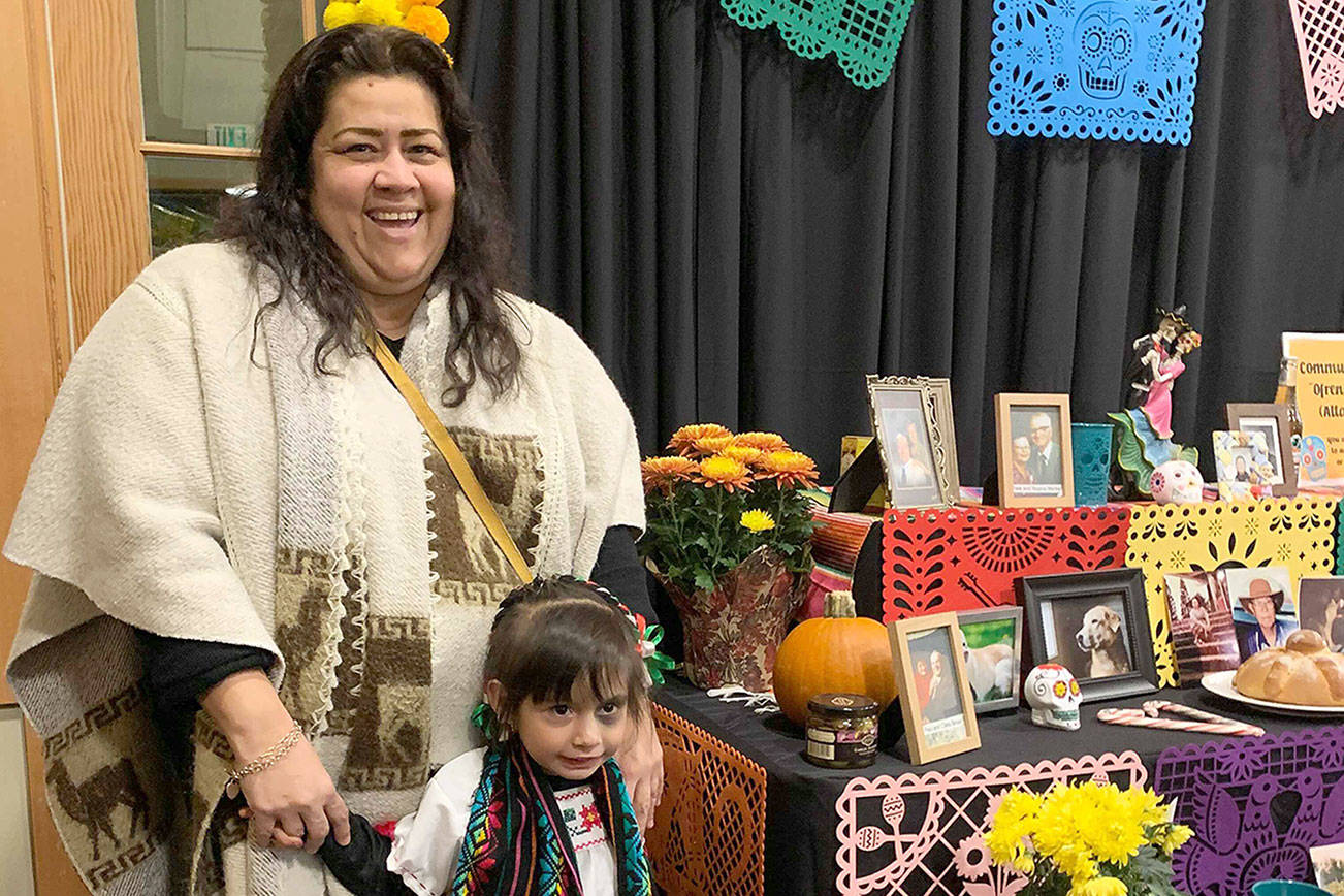 Natalie DeFord/staff photo                                Maria Monroy and her daughter Lupita Vasquez, 3 years old, in front of the community altar at the Issaquah Highlands Day of the Dead celebration.