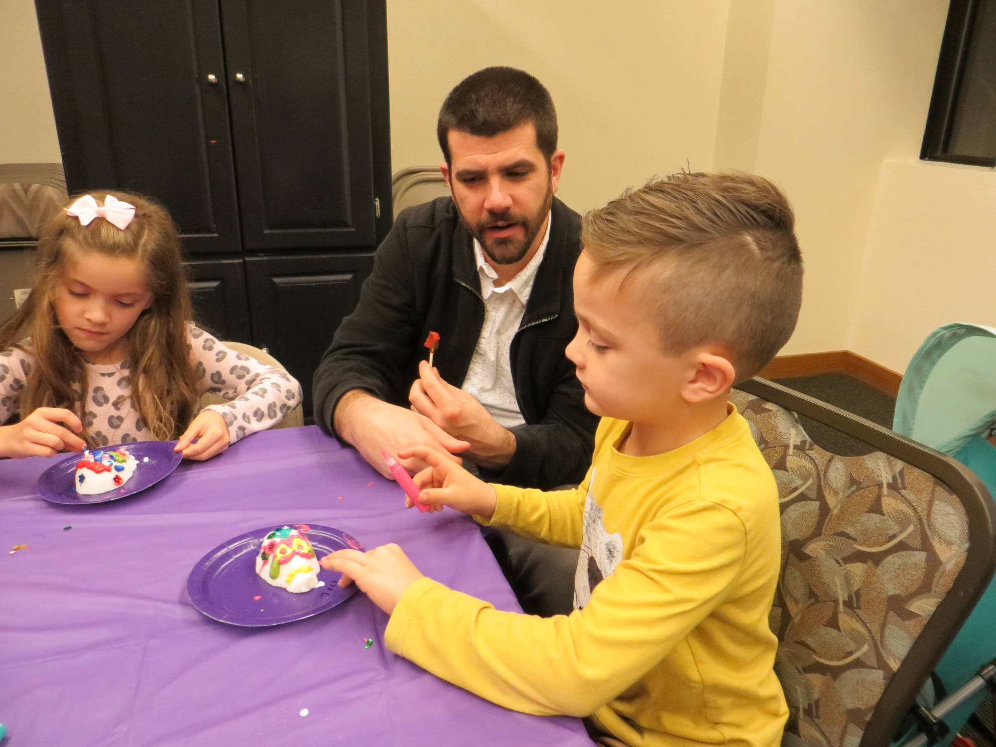 From left, Olivia, Brian and Jack McBride create sugar skulls at the Dia De Los Muertos celebration in downtown Issaquah. Samantha Pak/staff photo
