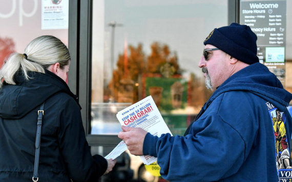 Kevin Flynn, right, a meat-cutter with the Marysville Albertsons, hands a leaflet to a shopper during an informational campaign on Wednesday, Nov. 9, 2022. Flynn was one of about a dozen grocery store workers handing out leaflets to shoppers about the proposed merger between Albertsons and Kroger. (Mike Henneke / The Herald)