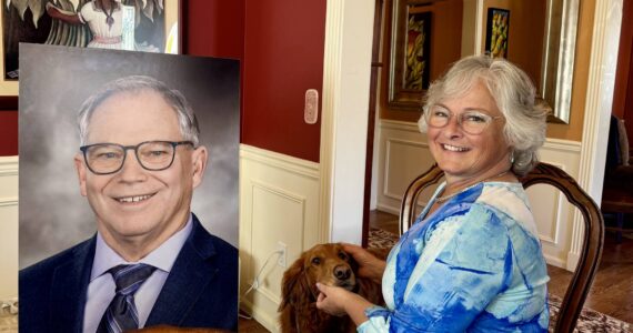 Sarah Perry and her dog, Sadie, sit with the photo of Bill Ramos used for his celebration of life in their Issaquah home, July 30, 2025. Perry said she keeps the photo in her home office so Ramos is always with her. (Grace Gorenflo/Valley Record)