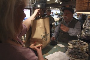 Store manager Tami Glauser hands Bill Glassey his purchase Monday morning at Lucky You! Glassey was the first through the door and the first to buy an item during Issaquah's first ever Cash Mob.