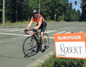 Rob Milligan rides past his 'Survivor' signs along the route.