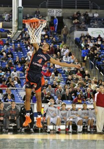 Sophomore Mattise Thybulle puts in a dunk against University as head coach Garrick Phillips looks on.
