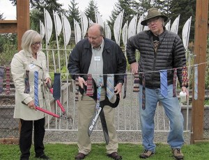 Sammamish Arts Commissioner Margaret Rosenow holds out garden cutters for Sammamish Mayor Tom Vance to use during the community gate ribbon cutting event Sept. 19. The city's ceremonial scissors could not cut the ribbon. Artist Garth Edwards looks on.