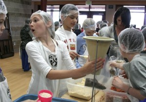 Sarah Schnebele holds up a bag for packing food to send to Africa. Each bag