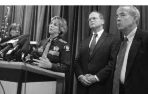 Sheriff Sue Rahr speaks to a room full of press members as District Court Presiding Judge Barbara Linde