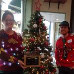 REI Golden Dumpster winners Donna Androwski and Guiness Ayers are nearly brighter than the Christmas tree in their festive sweaters. Nicole Jennings/staff photo