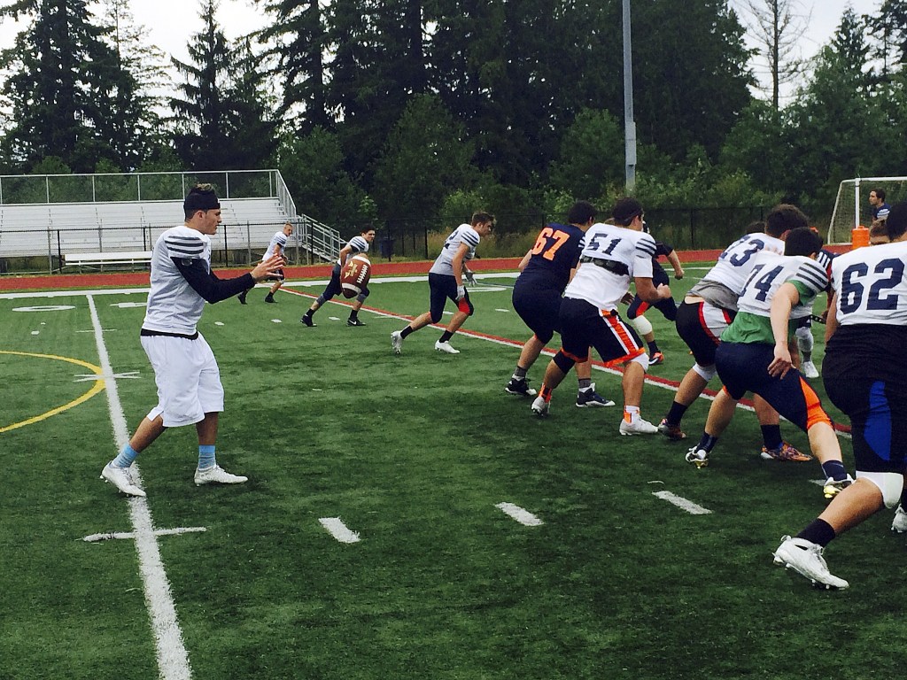 Shaun Scott, staff photo                                Eastside Catholic Crusaders starting quarterback Zach Lewis, left, takes a snap during a spring football practice session in June of 2016. Lewis led the Crusaders to the Class 3A state semifinals in his first season as the starting quarterback.