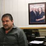 Jimmy Kathawa stands in his office at the Front Street market, in front of photos of his parents, left, and parents-in-law, right. Both sets of parents owned grocery stores. Nicole Jennings/staff photo