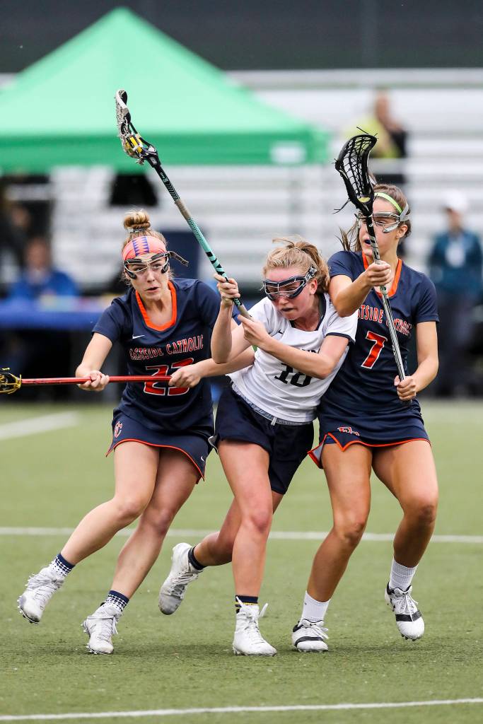 Photo courtesy of Rick Edelman/Rick Edelman Photography                                Eastside Catholic players Carlin Reilly, left, and Olivia Jacobsen, right, put pressure on Bainbridge Island midfielder Kiera Havill during the state championship game on May 19 in Tukwila. Eastside Catholic defeated Bainbridge Island 16-11.