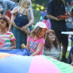 Alicia De Paz, 5, laughs as she and other children play with a large, colorful parachute at the Sammamish Concerts in the Park July 13. Megan Campbell/staff photo