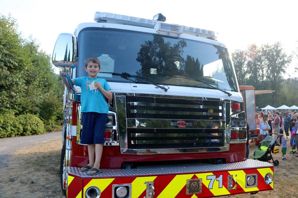 Griffin Bishop stands on the front of a fire truck after Issaquah firefighters gave him a tour of the interior. (Evan Pappas/Staff Photo)
