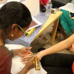 Left, dressed in a traditional Indian sari, Sangeetha Madanagopal paints henna body art on attendees. The designs last for about two weeks. Nicole Jennings/staff photo