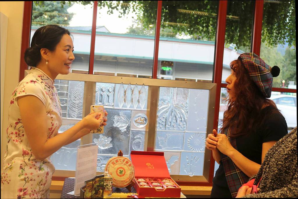 Joanna Zhang Partlow describes to Scottish Country Dance instructor and Adult Services Librarian Karla Anderson the Chinese art form of inner painting. Nicole Jennings/staff photo