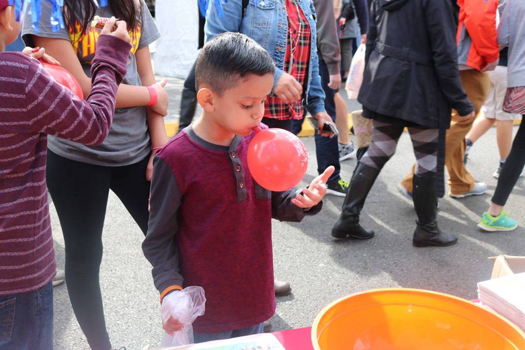 A boy blows up a balloon at a booth along East Sunset Way. Nicole Jennings/staff photo