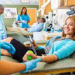 Woman donating blood in busy donation center