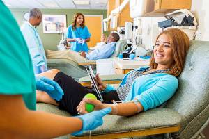 Woman donating blood in busy donation center