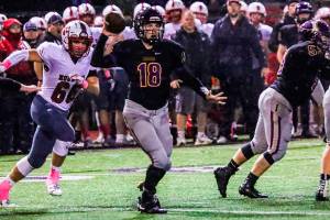Issaquah Eagles quarterback Trevor Morine, center, unleashes a pass while being pressured by Mount Si defensive player Carlos Ortiz in the first half of play. Mount Si defeated Issaquah 38-6 on Oct. 5 at Gary Moore Stadium in Issaquah. Photo courtesy of Don Borin/Stop Action Photography