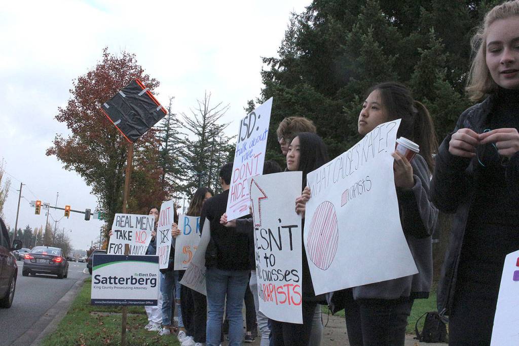 Skyline High School students and community protest perpetuation of rape culture following ISD lawsuit. Sasha Burckhardt, senior, holds a sign that reads, ISD: Talk about rape, dont hide it. Emily Tang and Teesoo Yoon, seniors, holds a sign that reads, What causes rape? Rapists. Madison Miller/staff photo.